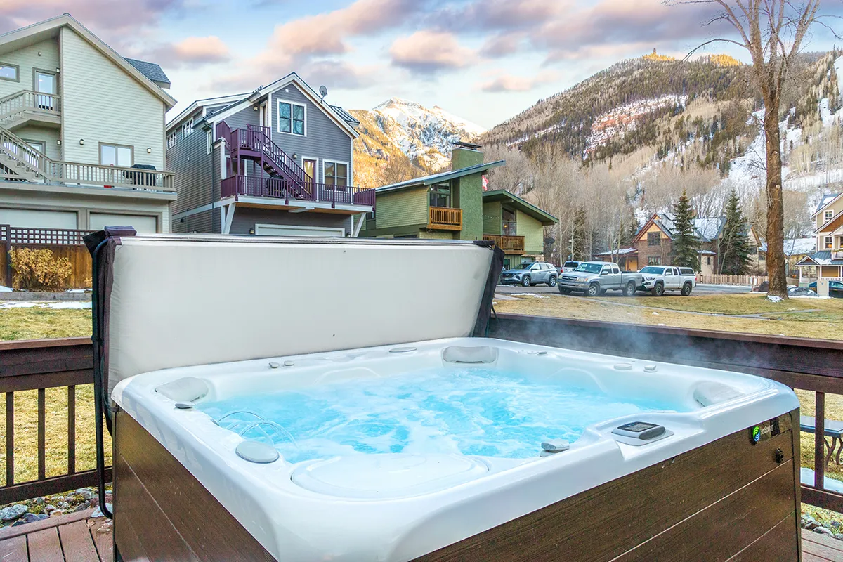 This exterior shot captures a hot tub with sweeping mountain views, surrounded by nearby houses. The image conveys a sense of relaxation and community, with the inviting waters of the hot tub in the foreground and the tranquil mountains beyond.